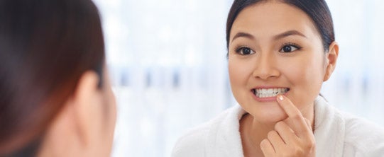 Mujer mirando sus dientes en un espejo 